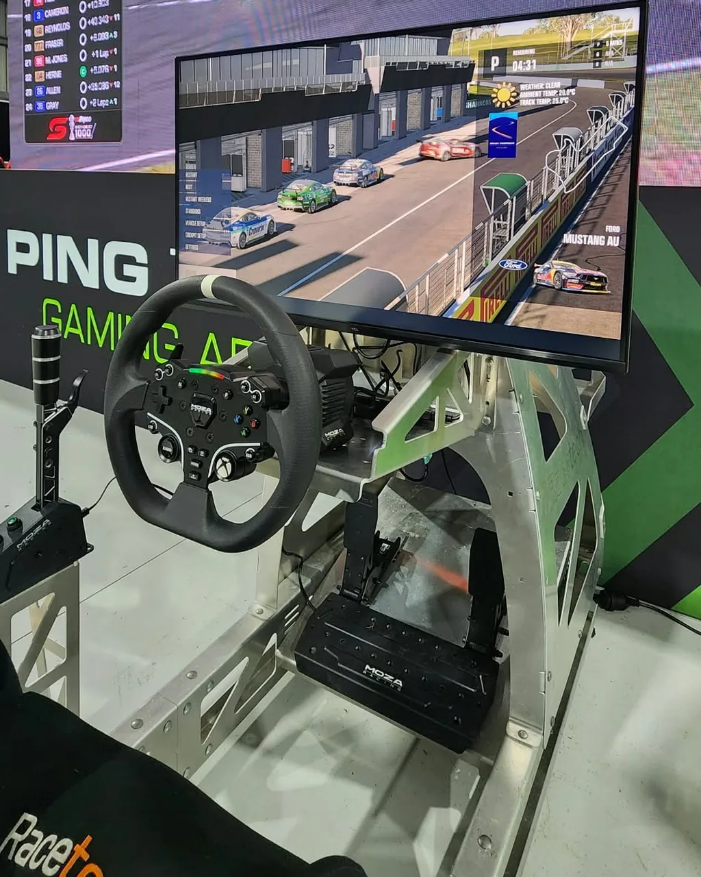 The TCL 32G64 on a Ping Zero Racetech sim rig with a MOZA wheel and shifter at Great Race Day, with the Bathurst 1000 on the big screen behind